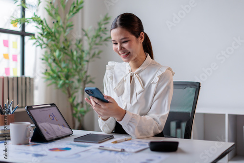 Foto Smiling young asian business woman analyzing financial data on a digital tablet