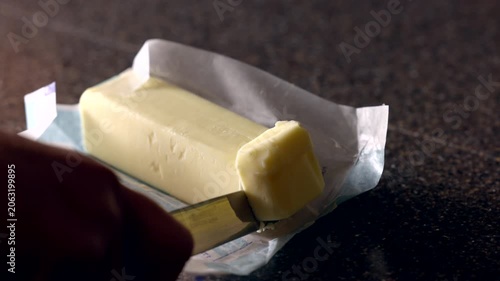 close up of a knife slicing a bar of butter for cooking in a home kitchen
