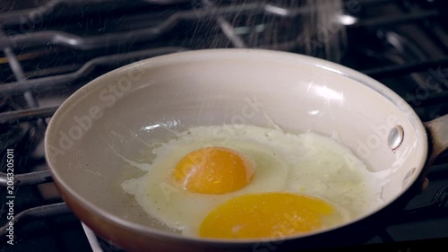 Frying eggs in a pan. Yellow yolks glisten over a lightly cooked white.