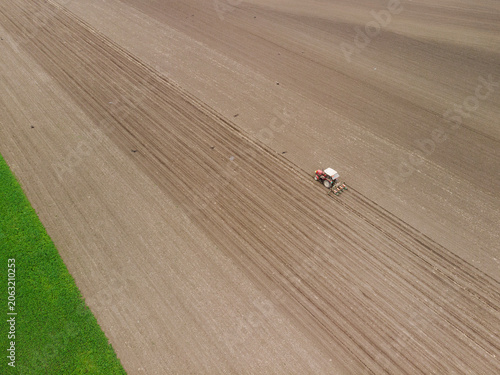 Aerial shot of a tractor fertilizing a agriculture crop fields