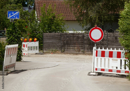 Road closed for maintenance work and repaving, stop signal and red and white barrier with warning lights