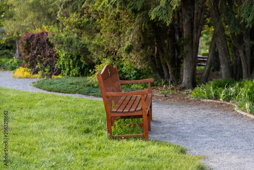 Wooden bench near path in park during spring season. Ornamental Gardens in Ottawa, Canada.