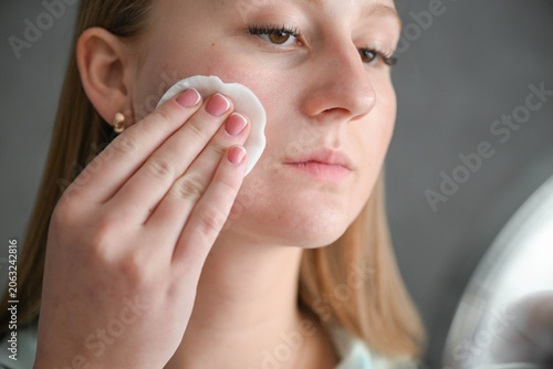 Принти на полотні Young woman with acne-prone skin removing makeup and cleansing face with cotton pad