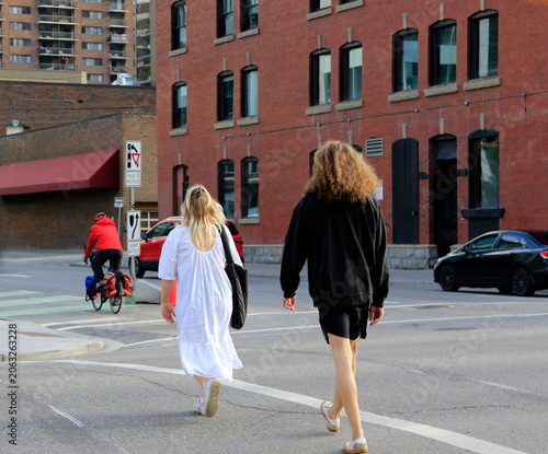 Un homme vêtu de noir et une femme vêtue de blanc traversent une rue de la ville de Calgary.