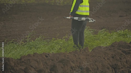 Official wearing high visibility vest standing in field holding checkered flag ready to start tractor race event at agricultural exhibition