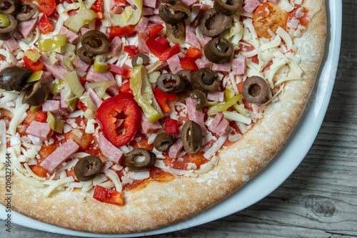 Pizza on plate. Freshly sliced pizza displayed on clean surface. Single slice of pizza with toppings on plain white dish