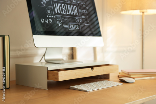 Foto Workplace with computer monitor on riser stand, keyboard, mouse and books in roo