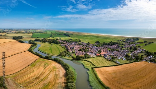 rural panorama vista showing a village in the countryside with farmlands fields river on a summers day aerial view overlooking the coastal landscape agricultural village life in lincolnshire