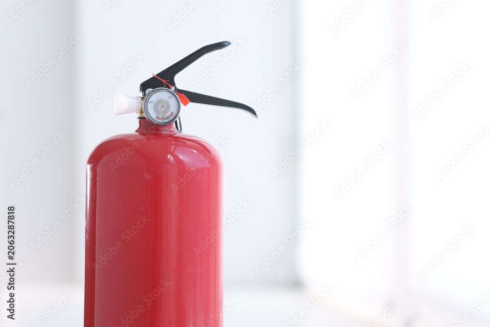 Obraz premium One red fire extinguisher near white wall indoors, closeup. Space for text