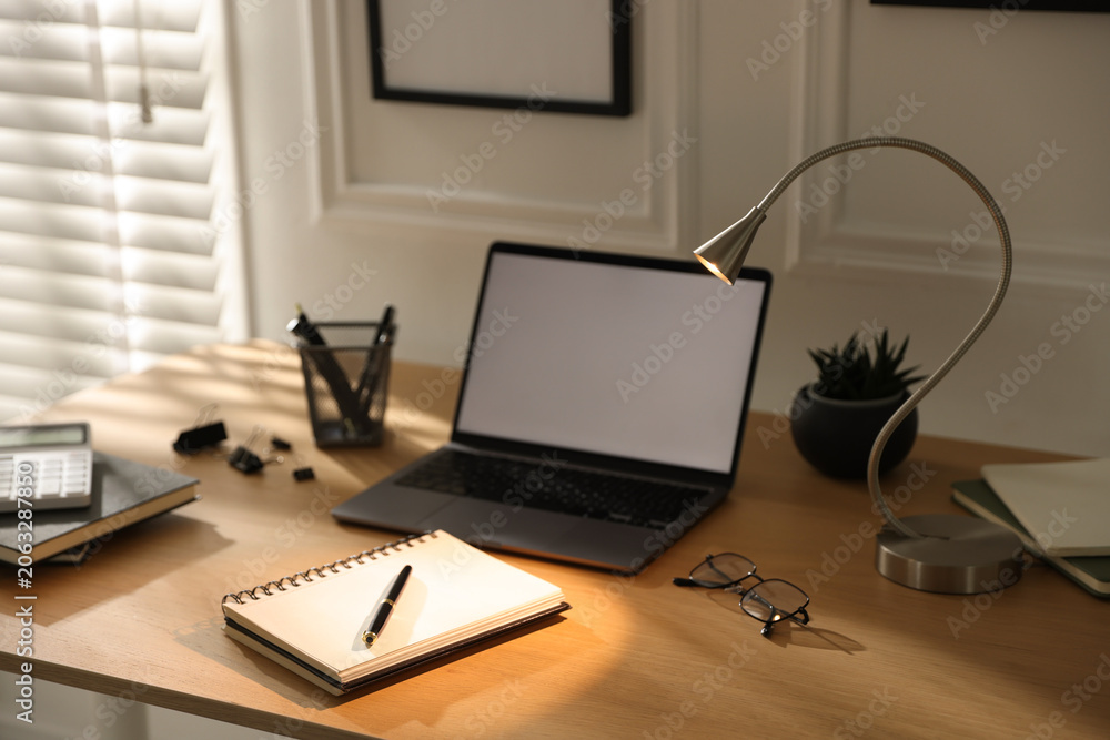 Naklejka premium Stylish workplace with lamp, laptop and stationery indoors