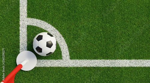 Top-down view of a classic soccer ball placed in the corner arc next to a red flag on a green grass pitch