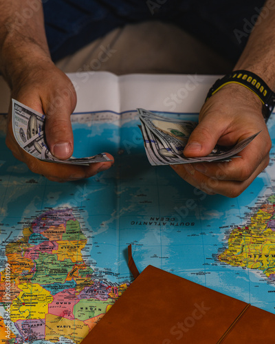 Planning a travel budget with cash and a world map for the upcoming trip