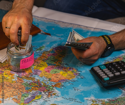 Planning a trip by adding cash to the travel savings jar on a world map