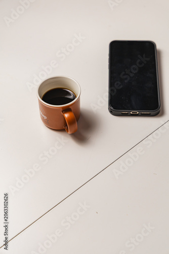 Cozy still life: brown ceramic cup beside smartphone on tabletop