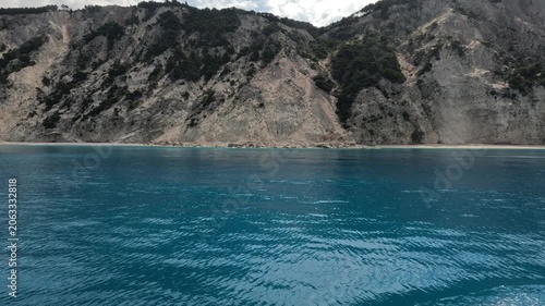Scenic view of dramatic coastal cliffs shaped by erosion and landslides along the shoreline of Ithaca Island in the Ionian Sea, Greece. Deep blue water contrasts with rocky mountains