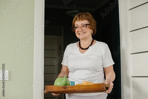 Photography Senior woman smiling offering breakfast tray at home