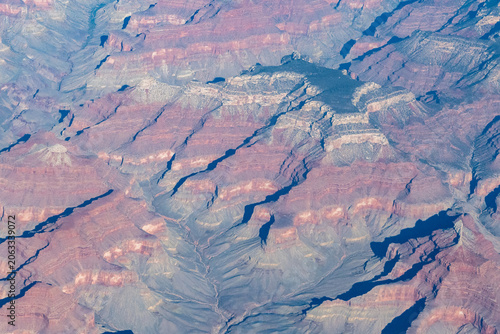 Aerial view of the Grand Canyon's layered canyon walls in Grand Canyon National Park, Arizona, USA. The rocks exhibit striking bands of red, orange, and gray hues, highlighting the geological history.