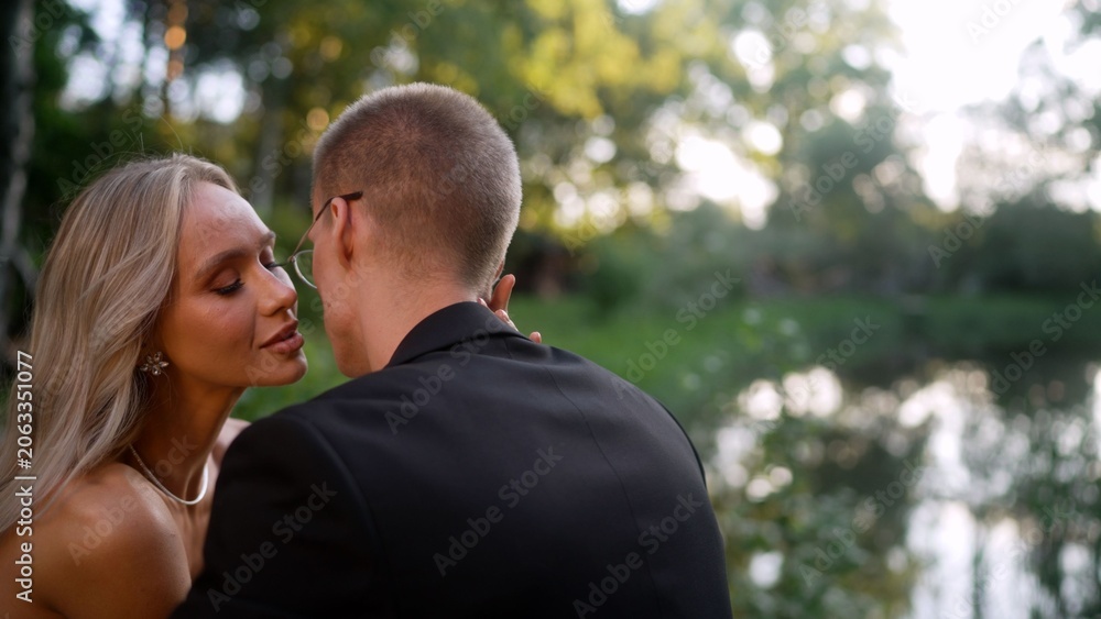 Naklejka premium romantic couple embracing near lake at sunset