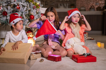 Smiling girl hugs a soft teddy bear gift beside the Christmas tree during a joyful family holiday celebration.