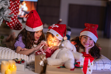 Happy children play with soft fake snow by a window during a festive Christmas morning celebration indoors at home together.