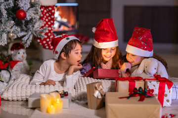 Happy children play with soft fake snow by a window during a festive Christmas morning celebration indoors at home together.