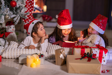 Happy children play with soft fake snow by a window during a festive Christmas morning celebration indoors at home together.