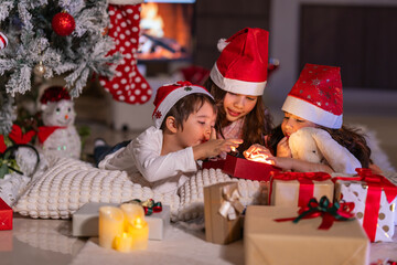 Happy children play with soft fake snow by a window during a festive Christmas morning celebration indoors at home together.