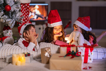 Happy children play with soft fake snow by a window during a festive Christmas morning celebration indoors at home together.