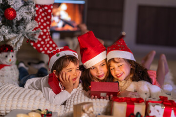Happy children play with soft fake snow by a window during a festive Christmas morning celebration indoors at home together.
