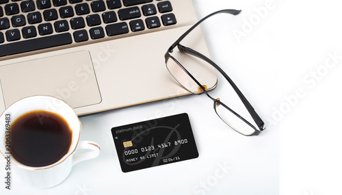Mobile banking and digital wallet concept with premium black credit card, smartphone, and laptop on white table