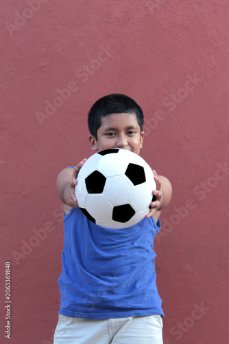 12-year-old Latino boy with dark skin plays with his soccer ball to practice for the game 