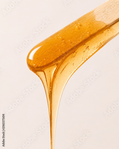 Golden Sugaring Wax Stretching Between Wooden Spatulas