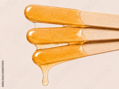 Golden Sugaring Wax Stretching Between Wooden Spatulas