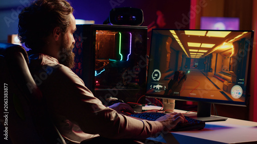 Foto Man playing first person shooter video game with automatic gun shooting laser bullets at flying robotic foes, gamer competing in PvP online multiplayer game tourney against opponents