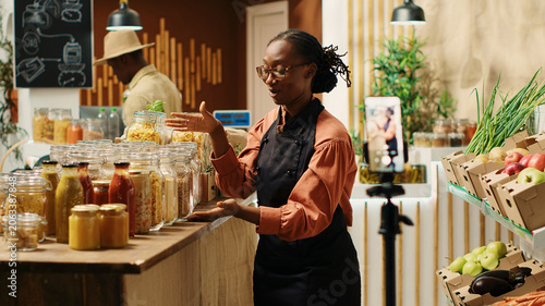 Tableau sur toile Eco store employee recording commercial video on social media to promote fresh homegrown produce and chemical free pantry items