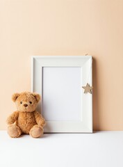Empty white frame and fuzzy teddy bear sit on table. Minimalist composition with soft peach wall background. Baby room decor or nursery theme mock-up idea.