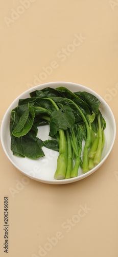 High angle view of blanched Chinese broccoli arranged on a white ceramic plate.