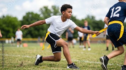 African american teen reaching for yellow flag during outdoor flag football practice on grassy field. Young athlete training with teammates in a competitive youth sports drill.
