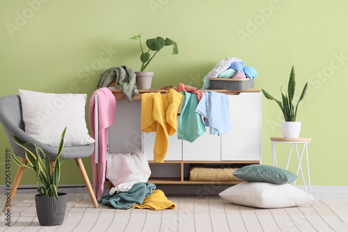 Fotografie Messy room interior with clothes piled on furniture and floor, disorganized livi