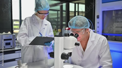 Professional Scientist Team Record Microscope Observation Data On Clipboard