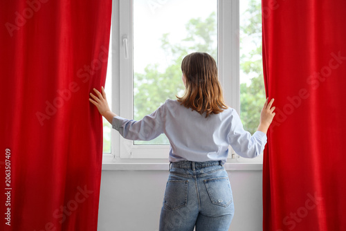 Young woman opening red cur...
