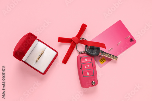 Gift keys of new car, credit card and engagement ring on pink background