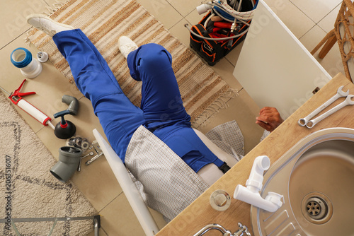 Mature male plumber lying o...