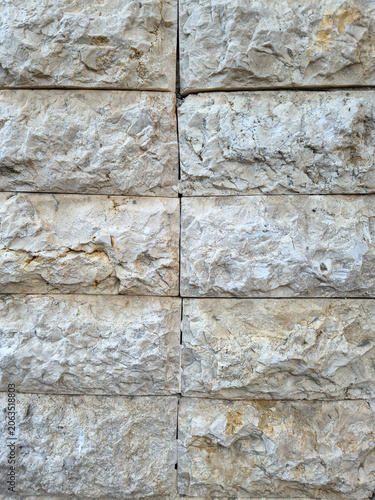 Detailed of rugged, uneven natural rock wall surface in light neutral tones