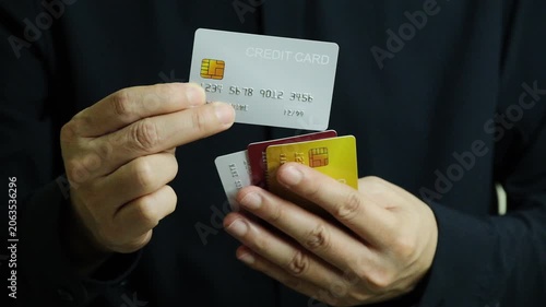 Close up of hand human holding multiple color credit cards, choosing a red card for payment, concept of consumerism, financial management, debt and cashless society and saving money	