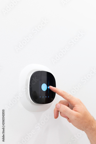 Obraz na płótnie Close up view of hand touching smart digital thermostat screen on white wall to