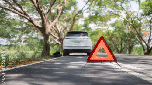 Fotografie Car breaks down on a quiet road and a person inspects the vehicle with a warning