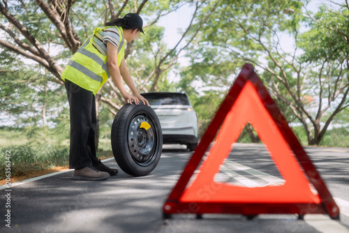 Foto Person holds a spare tire on a road with trees and a car in the background durin