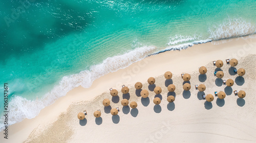 Aerial beach with straw umbrellas casting shadows on white sand