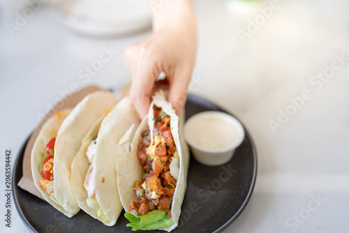 Foto hand picking up mexican burrito with dipping sauce from plate